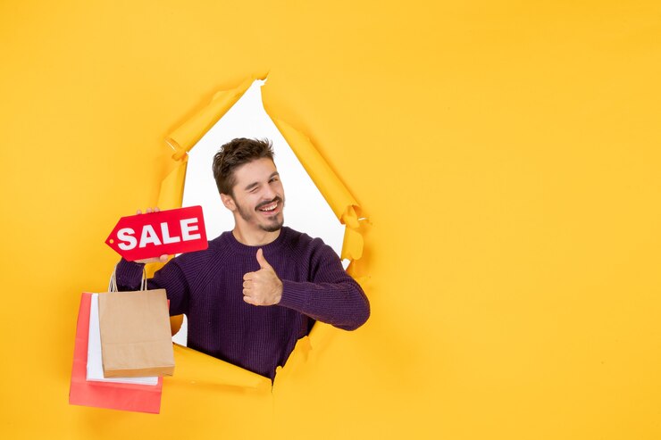 front-view-young-male-holding-little-packages-sale-writing-yellow-background-new-year-color-holiday-gift-christmas_140725-139786