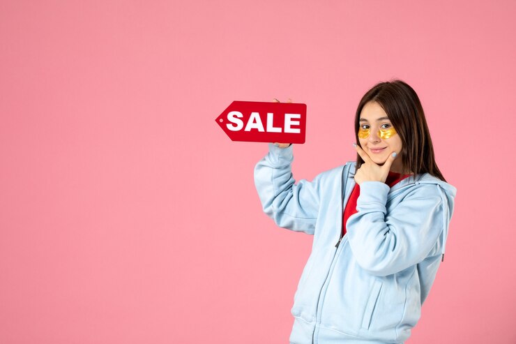 front-view-young-woman-with-eye-patches-holding-red-sale-banner-pink-wall_140725-147940